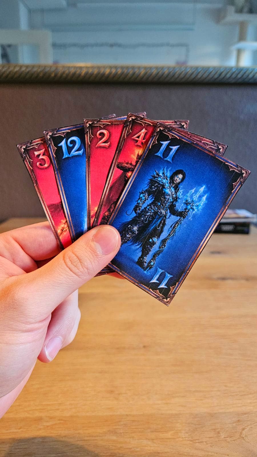 A hand holding five home printed Crowns cards in red and blue